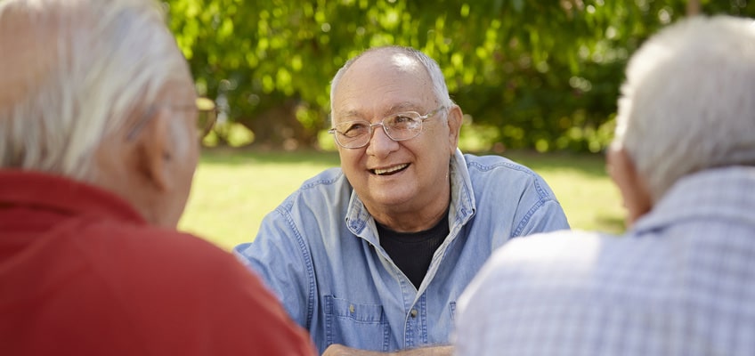 A man outside with two other men laughing.