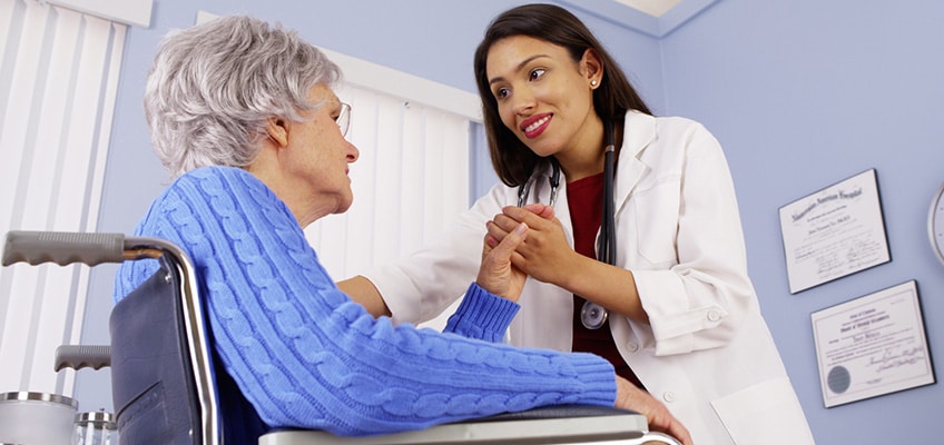 A doctor leaning in to hold the hand of a patient.